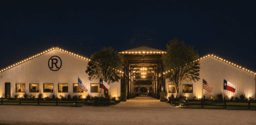 The Western Pavilion at night, outlined in lights with Texas and American flags