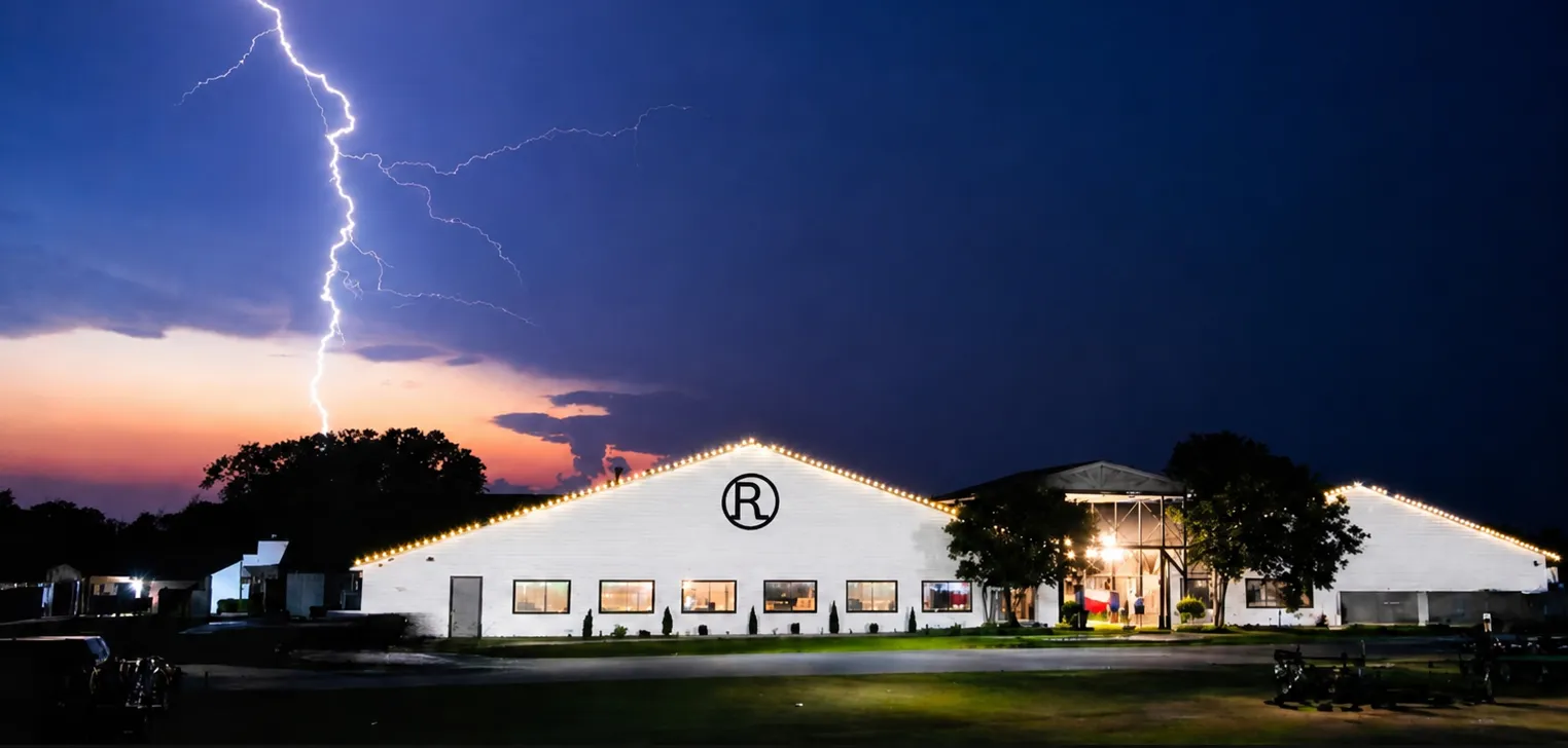 The Circle R Ranch pavilion lit up at dusk as lightning breaks over the ranch